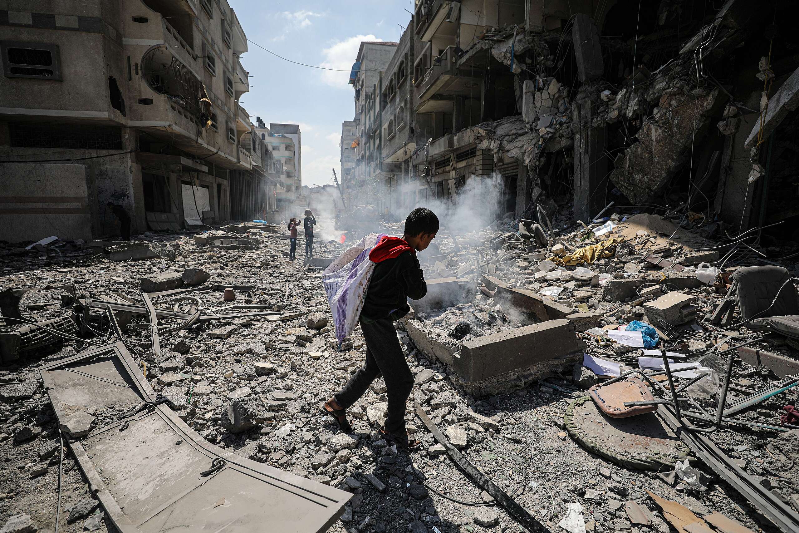 Photo of a Palestinian child walking through the ruins of Gaza carrying a bag. Photo credit: Anadolu Agency